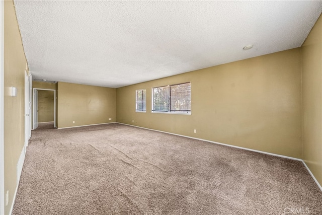 empty room with carpet floors, a textured ceiling, and baseboards