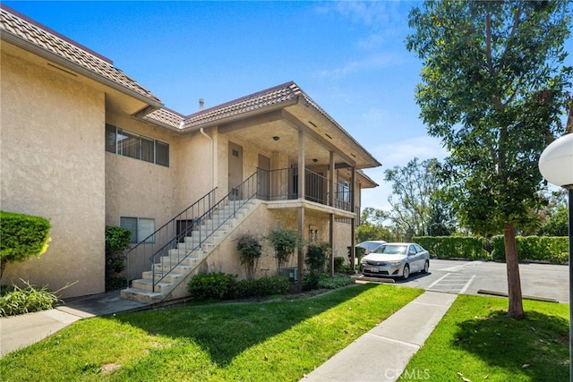 view of side of home with a lawn, stucco siding, and stairway