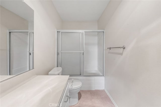 full bath featuring tile patterned flooring, vanity, baseboards, toilet, and shower / bath combination with glass door