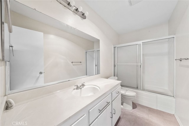 bathroom with vanity, tile patterned floors, combined bath / shower with glass door, and toilet