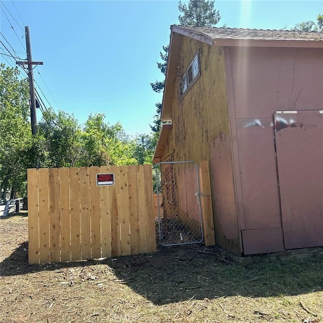 view of side of home with roof with shingles and fence