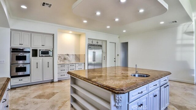 8531 10th St, Downey, CA 90241 - kitchen featuring built in appliances, dark stone counters, an island with sink, crown molding, and open shelves