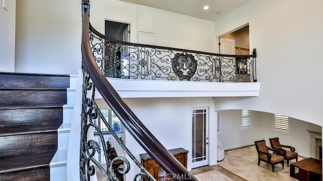 stairway featuring arched walkways, a high ceiling, recessed lighting, and a wealth of natural light