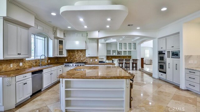 8531 10th St, Downey, CA 90241 - kitchen featuring open shelves, appliances with stainless steel finishes, dark stone countertops, a center island, and ornamental molding