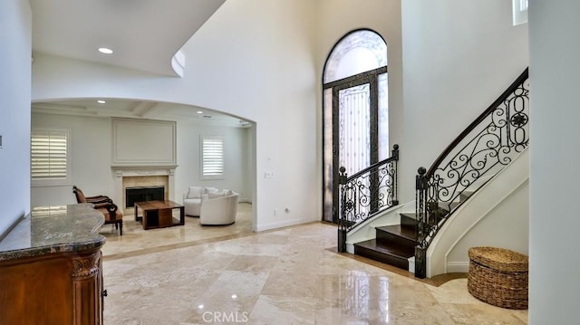 foyer featuring stairs, a fireplace, baseboards, a high ceiling, and recessed lighting