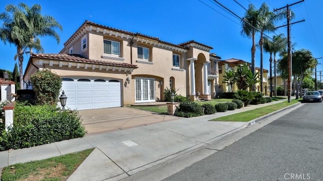 mediterranean / spanish house featuring stucco siding, a tiled roof, and concrete driveway