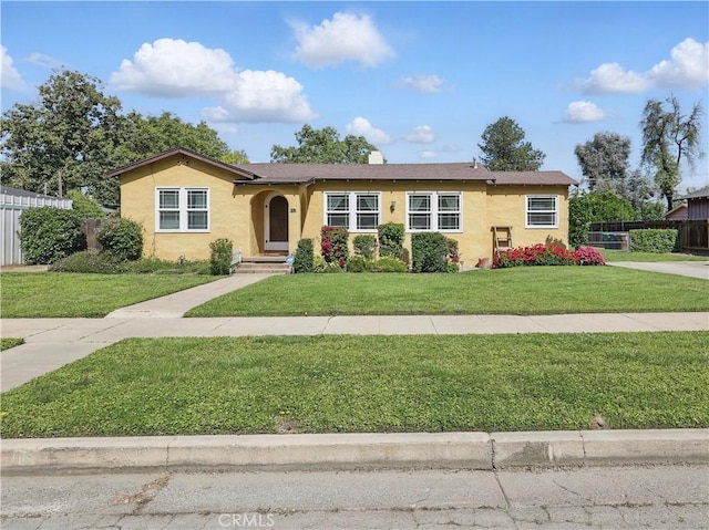 view of front facade with stucco siding, fence, and a front yard