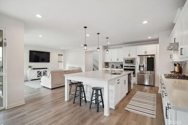 kitchen with light wood-style floors, a sink, appliances with stainless steel finishes, and backsplash