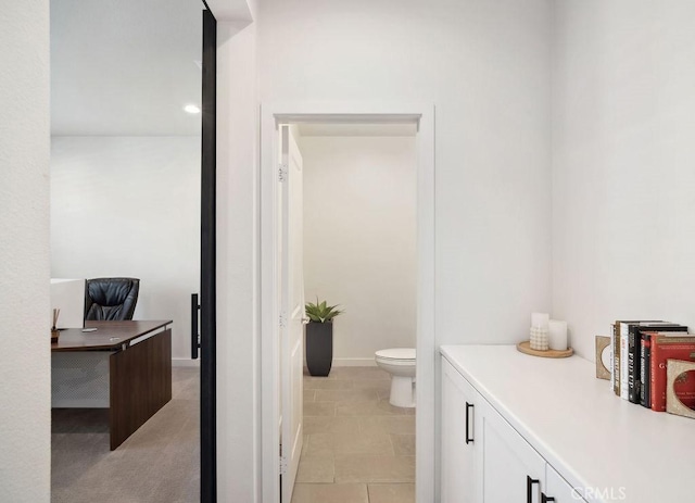 bathroom with toilet, baseboards, and tile patterned flooring
