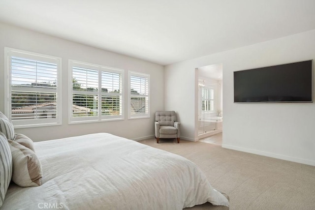 bedroom featuring baseboards, light carpet, and ensuite bathroom