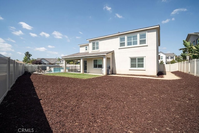 back of property with a fenced in pool, a fenced backyard, stucco siding, and a patio