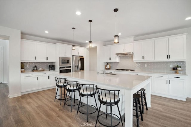 kitchen featuring a sink, appliances with stainless steel finishes, a breakfast bar, and light wood-type flooring