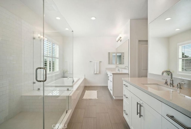 full bathroom with a bath, a shower stall, two vanities, a sink, and recessed lighting