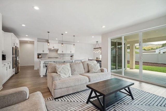 living area featuring recessed lighting, a notable chandelier, and light wood-type flooring