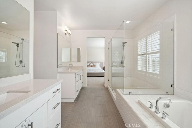 ensuite bathroom featuring two vanities, a shower stall, a sink, and a bath