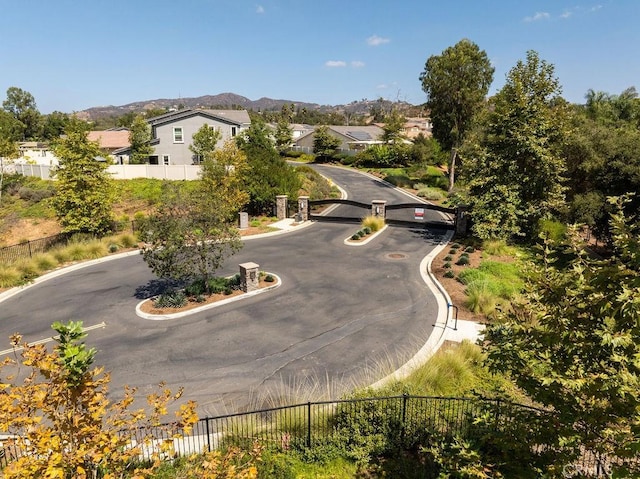 view of street with a residential view, a gated entry, a mountain view, and curbs