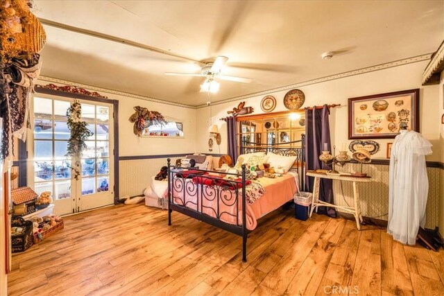 bedroom with a ceiling fan, french doors, hardwood / wood-style flooring, a wainscoted wall, and access to outside