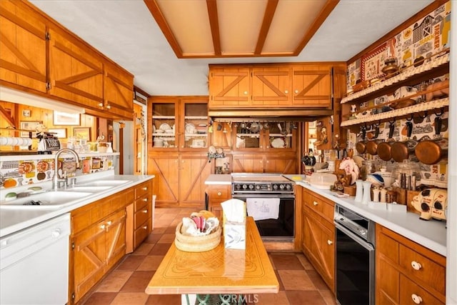 kitchen with a sink, dishwasher, light countertops, range, and light tile patterned floors