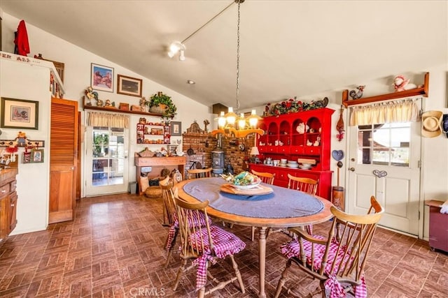 dining space featuring plenty of natural light, vaulted ceiling, brick patterned floor, and a chandelier