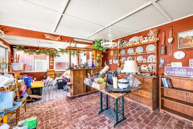 interior space featuring an inviting chandelier and brick floor