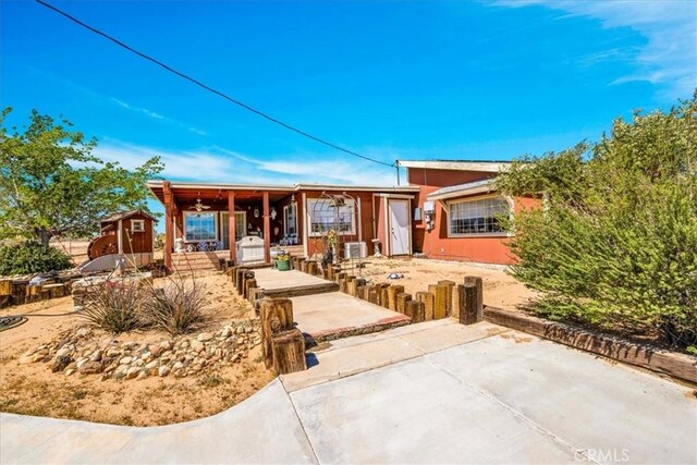 view of front of house featuring a porch, an outdoor structure, a patio area, and a storage unit