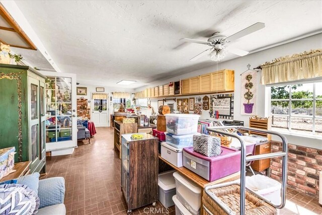 interior space with a ceiling fan, brick patterned floor, and a textured ceiling