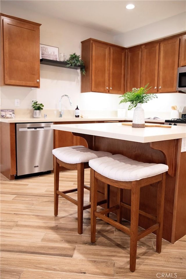 9369 Riberena Cir Unit 11, Atascadero, CA 93422 - kitchen featuring appliances with stainless steel finishes, light countertops, a kitchen breakfast bar, light wood-type flooring, and brown cabinetry
