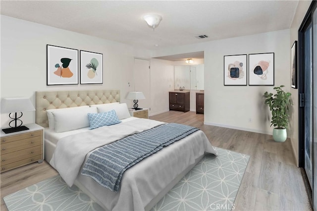 bedroom with baseboards, visible vents, light wood-style flooring, and ensuite bath