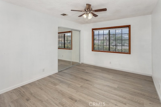spare room with a healthy amount of sunlight, ceiling fan, wood finished floors, and visible vents