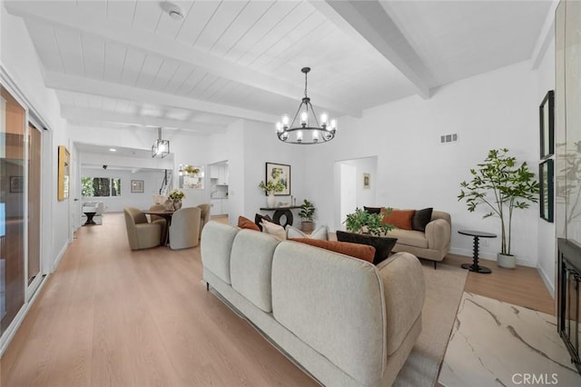 living room featuring beamed ceiling, light wood finished floors, a chandelier, and visible vents