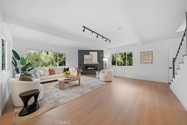 living room with plenty of natural light, wood finished floors, and stairway