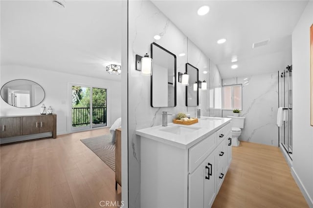 full bath with a sink, double vanity, toilet, and wood finished floors