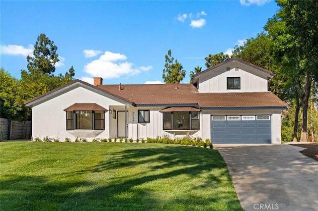 view of front of house featuring a front yard, a chimney, an attached garage, driveway, and a tile roof