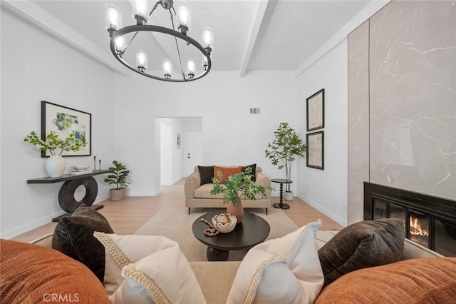living room with visible vents, beam ceiling, wood finished floors, a chandelier, and a premium fireplace