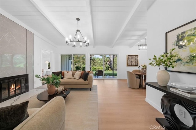 living area with a fireplace, light wood finished floors, beam ceiling, and a chandelier