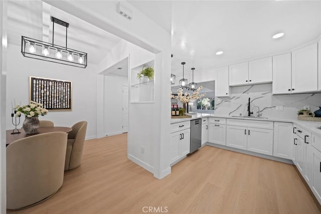 kitchen featuring a sink, light countertops, stainless steel dishwasher, and light wood finished floors