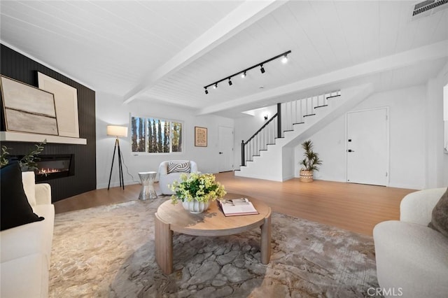 living room featuring visible vents, a large fireplace, beam ceiling, wood finished floors, and stairs