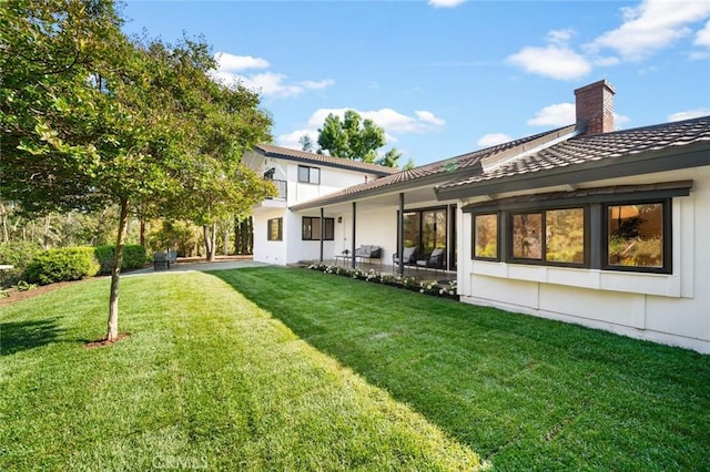 back of property with a lawn and a chimney
