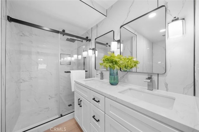 bathroom with double vanity, a sink, and a marble finish shower