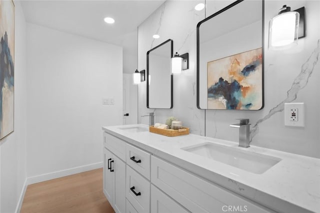 bathroom featuring double vanity, a sink, baseboards, and wood finished floors
