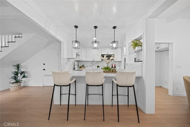 kitchen with a sink, a peninsula, white cabinets, and a kitchen breakfast bar