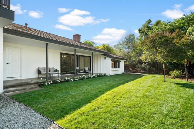 exterior space with board and batten siding, a yard, and a chimney