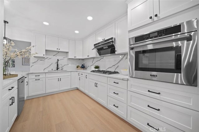 kitchen featuring a sink, appliances with stainless steel finishes, light wood-style flooring, and white cabinetry