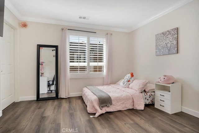 bedroom with baseboards, ornamental molding, wood finished floors, and visible vents