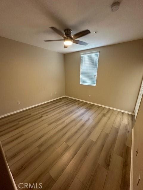 spare room featuring baseboards, ceiling fan, and wood finished floors