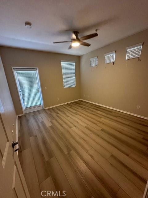 unfurnished room with baseboards, ceiling fan, and wood finished floors