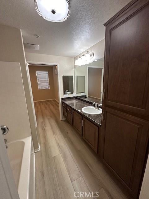 bathroom with vanity, a textured ceiling, and wood finished floors