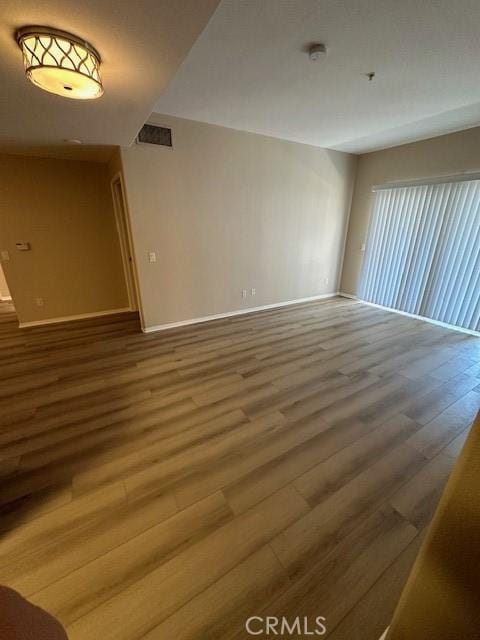 empty room featuring baseboards, visible vents, and wood finished floors