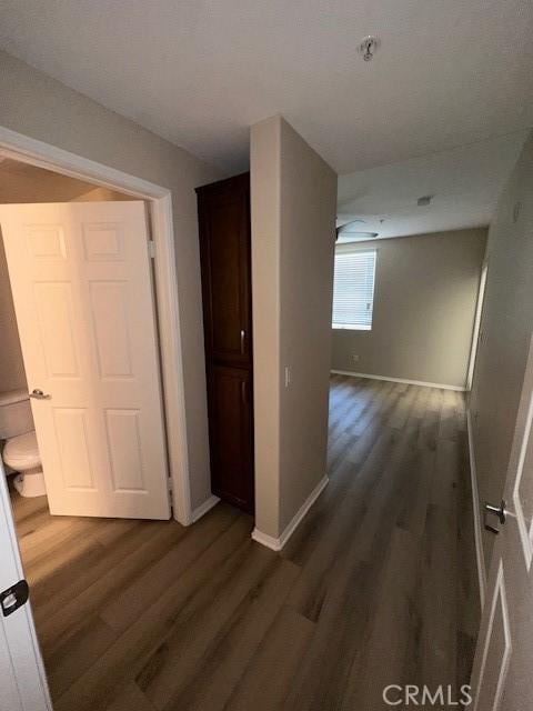 hallway featuring baseboards and dark wood finished floors