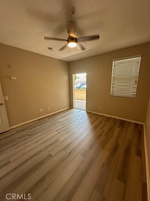 unfurnished room featuring baseboards, a ceiling fan, and wood finished floors